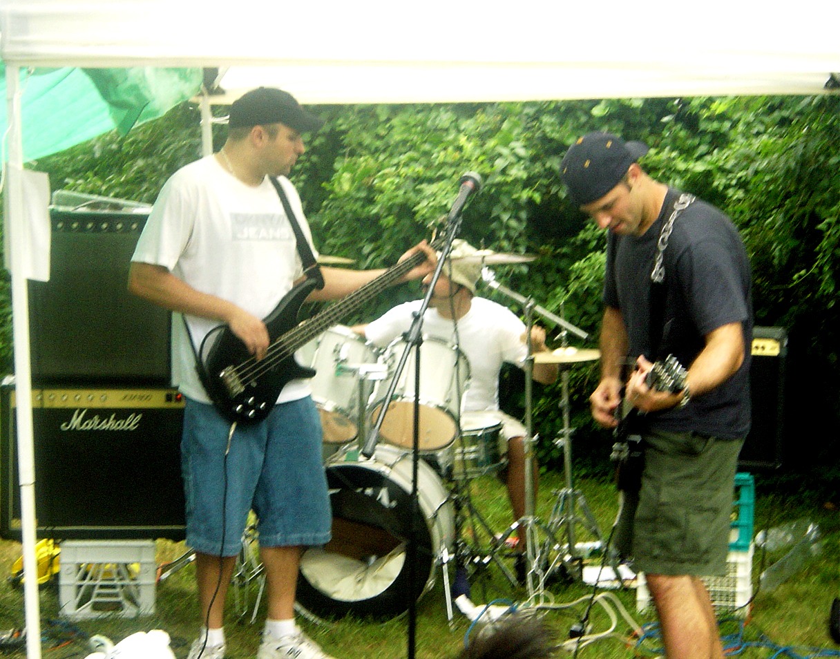 Live band performing with guitar, bass and drums at an outdoor event