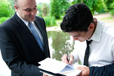 Newlywed signing a New York marriage license with guidance from a NY Marriages wedding officiant